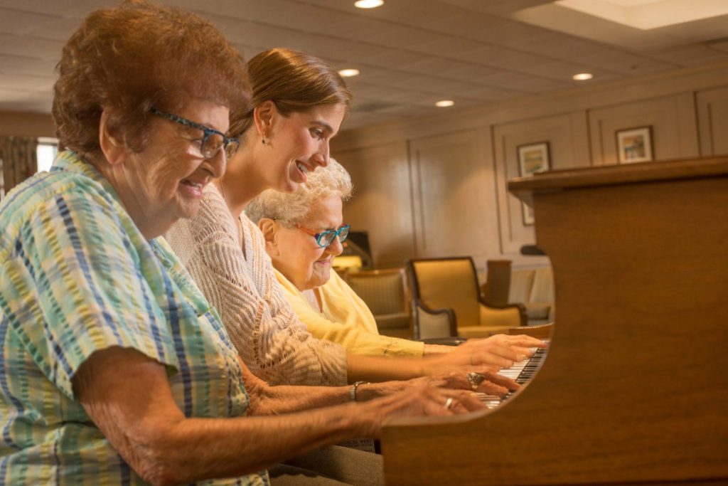 Residents and young lady playing piano together