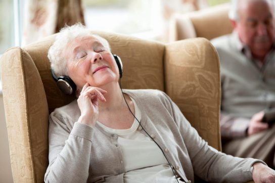 older woman listening to music through headphones