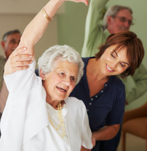 woman assisting an older woman in a stretch pose