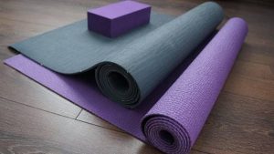 two partly rolled yoga mats, turquoise and purple, a purple yoga block