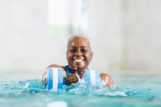 senior woman smiling and doing water aerobics