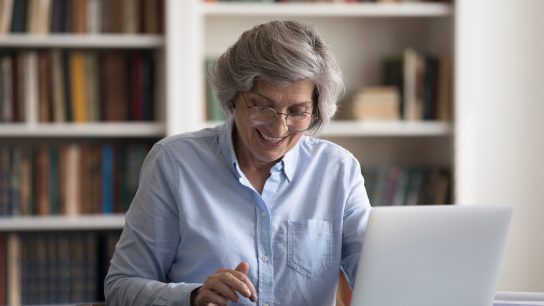 senior woman in her home library calculating the cost of independent living